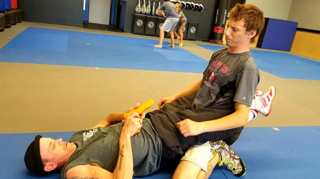 Combatives students train to get to their firearm with an attacker on top.
