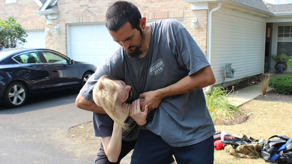 The girl turns her head and grabs the attacker’s hand.